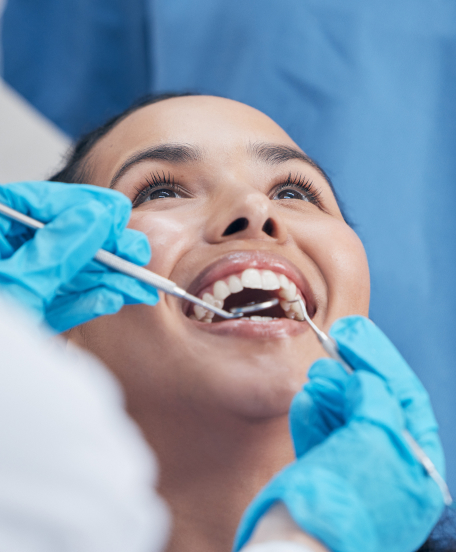 Dentist cleaning a patient's teeth with dental tools.